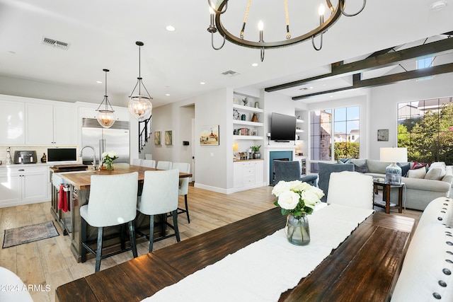 dining area featuring a chandelier, light hardwood / wood-style flooring, and built in features