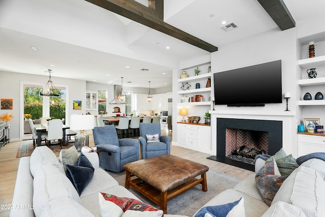 living room featuring beam ceiling, an inviting chandelier, built in shelves, and light hardwood / wood-style floors