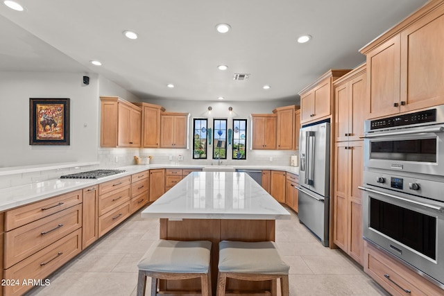 kitchen featuring a kitchen bar, light tile patterned floors, a kitchen island, and appliances with stainless steel finishes