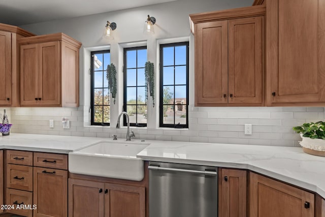 kitchen with stainless steel dishwasher, light stone countertops, sink, and decorative backsplash