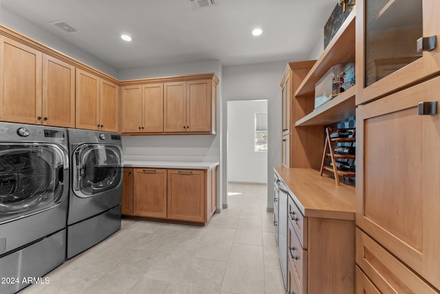 laundry room with washing machine and clothes dryer, cabinets, and light tile patterned floors