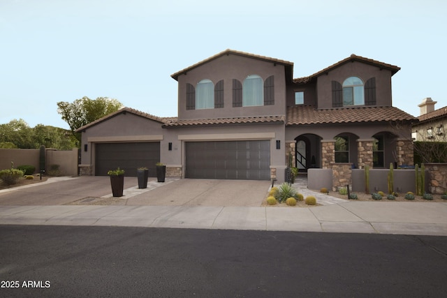 mediterranean / spanish home featuring stucco siding, an attached garage, fence, stone siding, and driveway