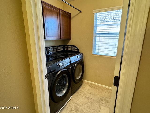 clothes washing area featuring cabinets and washer and clothes dryer