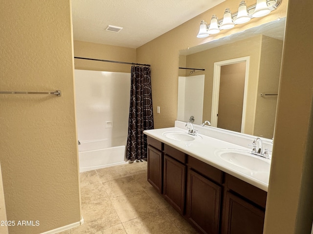 bathroom featuring a textured ceiling, shower / tub combo with curtain, and vanity