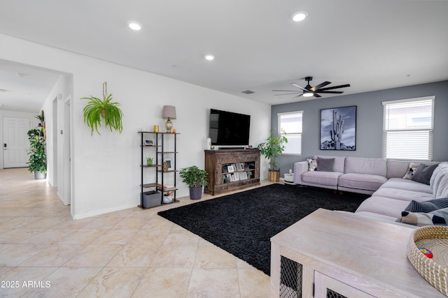tiled living room with a multi sided fireplace, plenty of natural light, and ceiling fan