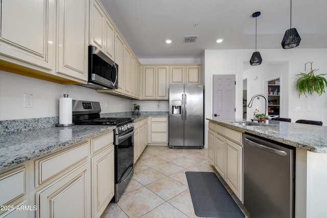 kitchen with pendant lighting, sink, a kitchen island with sink, stainless steel appliances, and light stone countertops