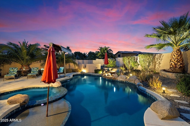 pool at dusk featuring a patio area