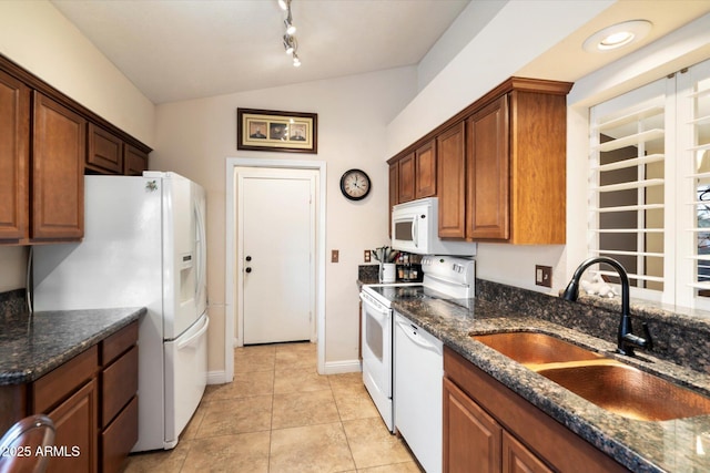 kitchen with sink, white appliances, dark stone countertops, and vaulted ceiling