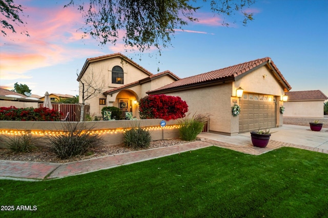 mediterranean / spanish house with a garage and a lawn