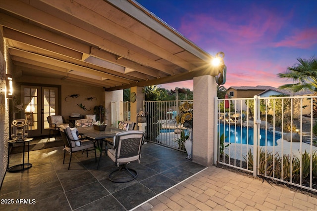 patio terrace at dusk featuring a fenced in pool and french doors