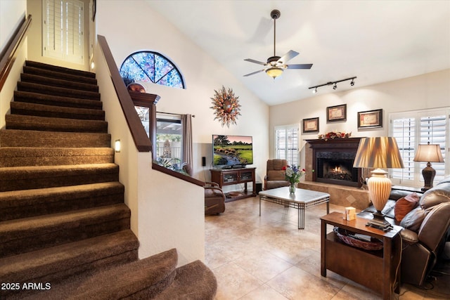 tiled living room featuring vaulted ceiling, ceiling fan, a wealth of natural light, and track lighting