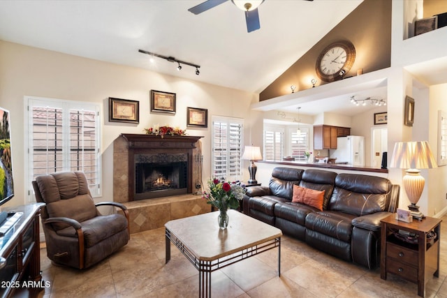 living room featuring vaulted ceiling, a premium fireplace, rail lighting, and ceiling fan