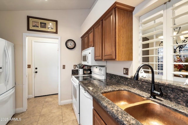 kitchen featuring white appliances, dark stone countertops, sink, vaulted ceiling, and light tile patterned floors