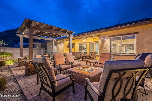 patio at night featuring a pergola and a fire pit