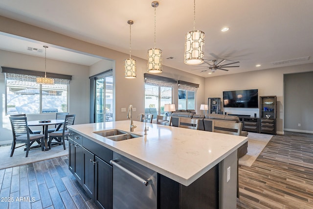 kitchen with pendant lighting, dark hardwood / wood-style flooring, a kitchen island with sink, and sink