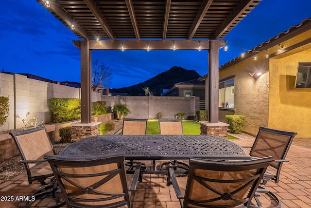 patio at night featuring a mountain view and a pergola