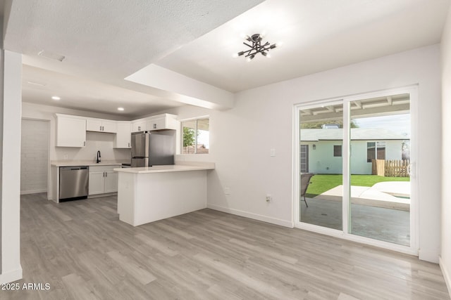 11842 N 30th Dr, Phoenix, AZ 85029 - kitchen with a peninsula, white cabinetry, light countertops, stainless steel appliances, and light wood finished floors