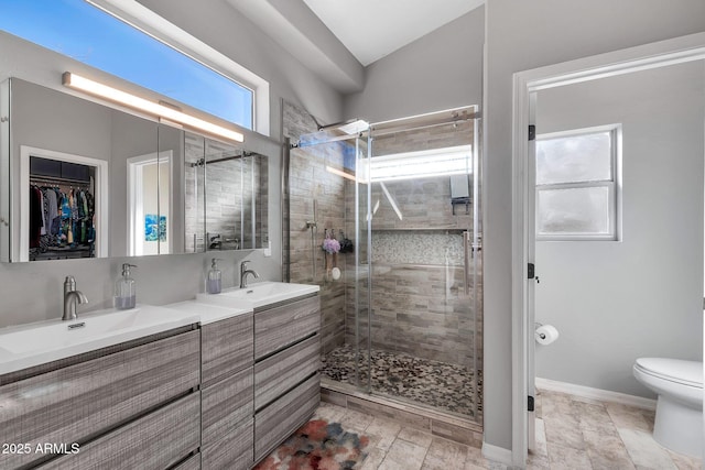 bathroom with a shower with shower door, toilet, and vanity