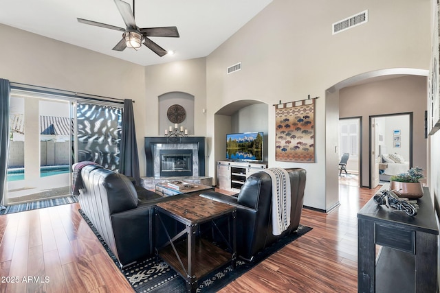 living room with ceiling fan, wood-type flooring, and a towering ceiling