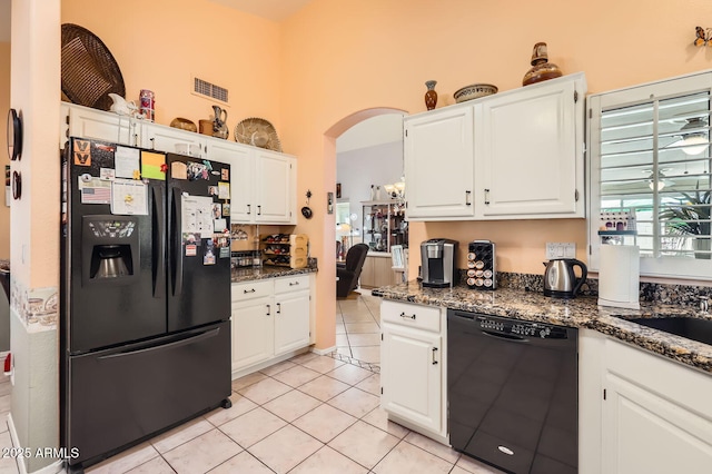 kitchen with light tile patterned floors, black appliances, white cabinets, and arched walkways