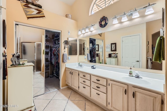 bathroom featuring tile patterned floors, a walk in closet, double vanity, and a sink