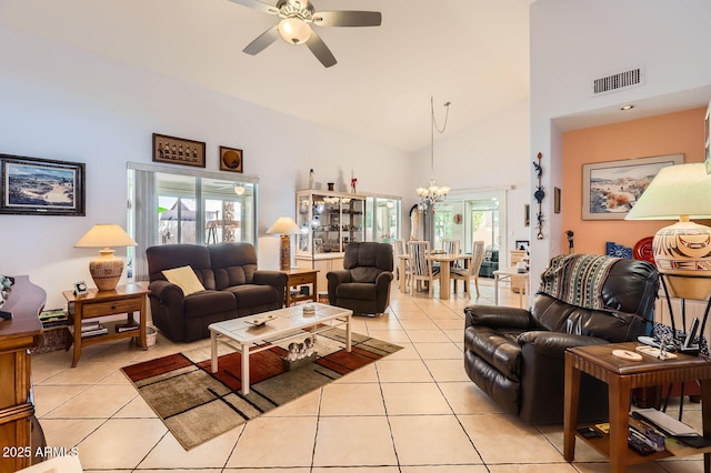 living room featuring light tile patterned floors, visible vents, high vaulted ceiling, and ceiling fan with notable chandelier