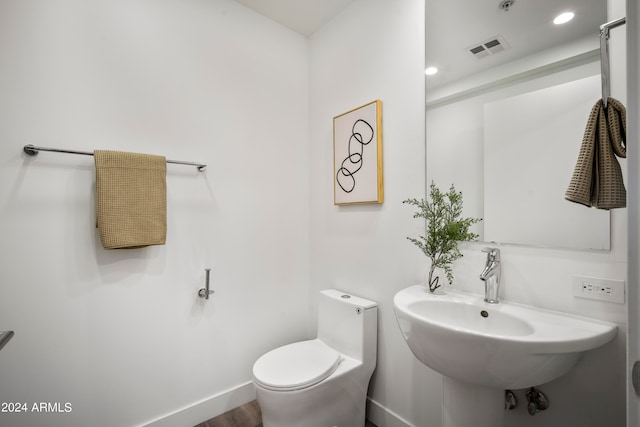 bathroom with hardwood / wood-style flooring, sink, and toilet