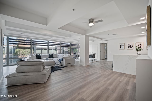 living room featuring light hardwood / wood-style flooring, a tray ceiling, and ceiling fan