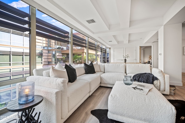 living room featuring beam ceiling, light hardwood / wood-style floors, and a wealth of natural light