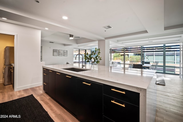 kitchen featuring light hardwood / wood-style flooring, a center island with sink, ceiling fan, and sink