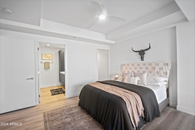 bedroom featuring wood-type flooring, ensuite bathroom, and ceiling fan