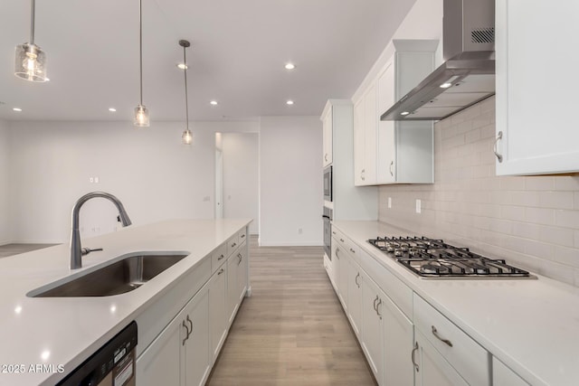 kitchen featuring appliances with stainless steel finishes, decorative light fixtures, white cabinets, and wall chimney exhaust hood