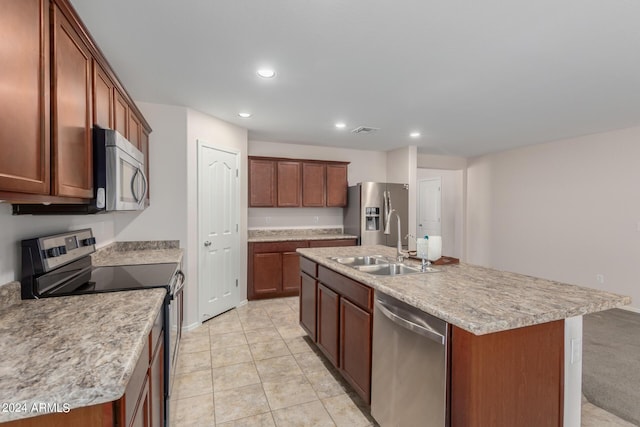 kitchen with sink, light tile patterned floors, stainless steel appliances, and an island with sink