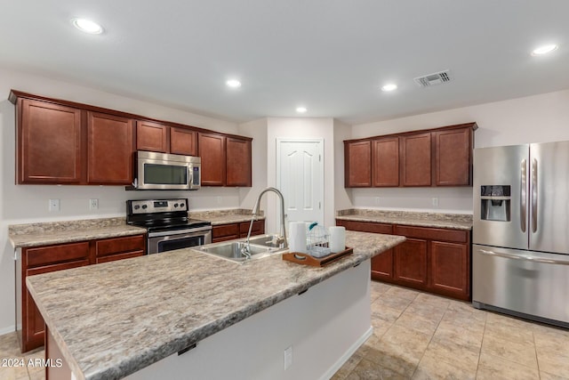 kitchen with stainless steel appliances, sink, and a center island with sink