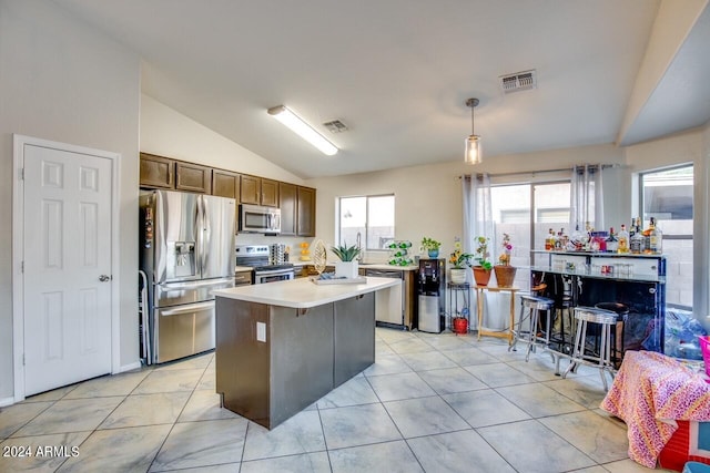 kitchen featuring stainless steel appliances, lofted ceiling, pendant lighting, and light tile patterned floors