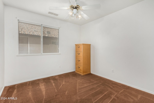 spare room featuring ceiling fan and dark carpet