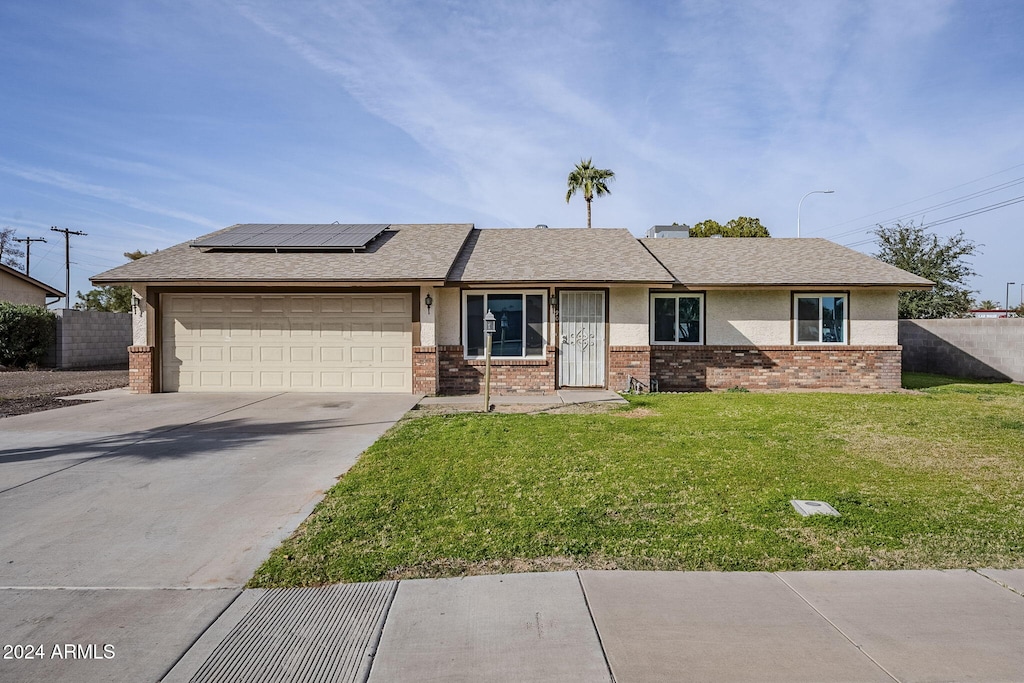 view of front of property with a front lawn, a garage, and solar panels