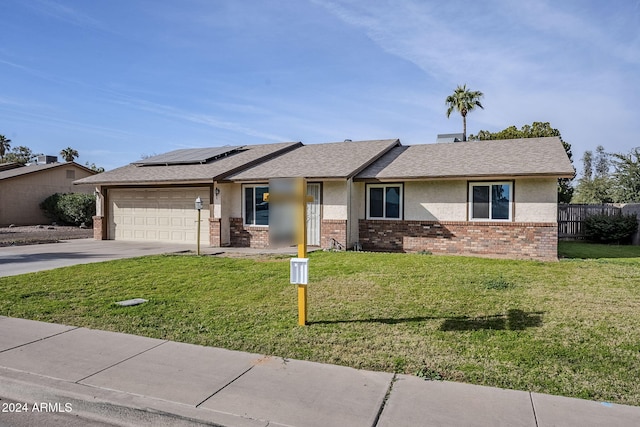 ranch-style home with solar panels, a garage, and a front yard