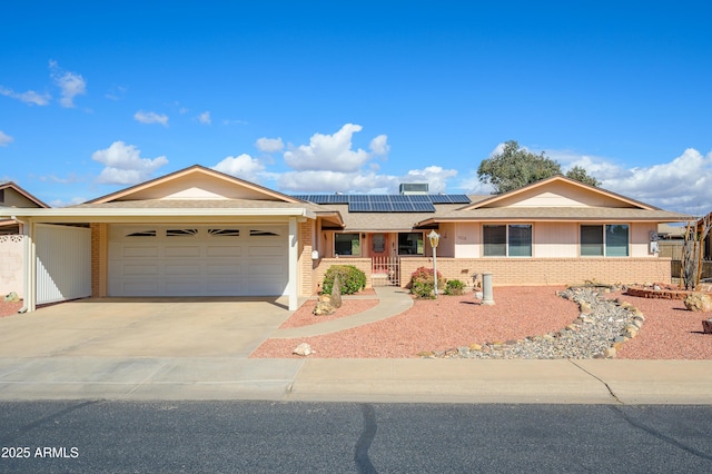 ranch-style home with concrete driveway, brick siding, an attached garage, and solar panels