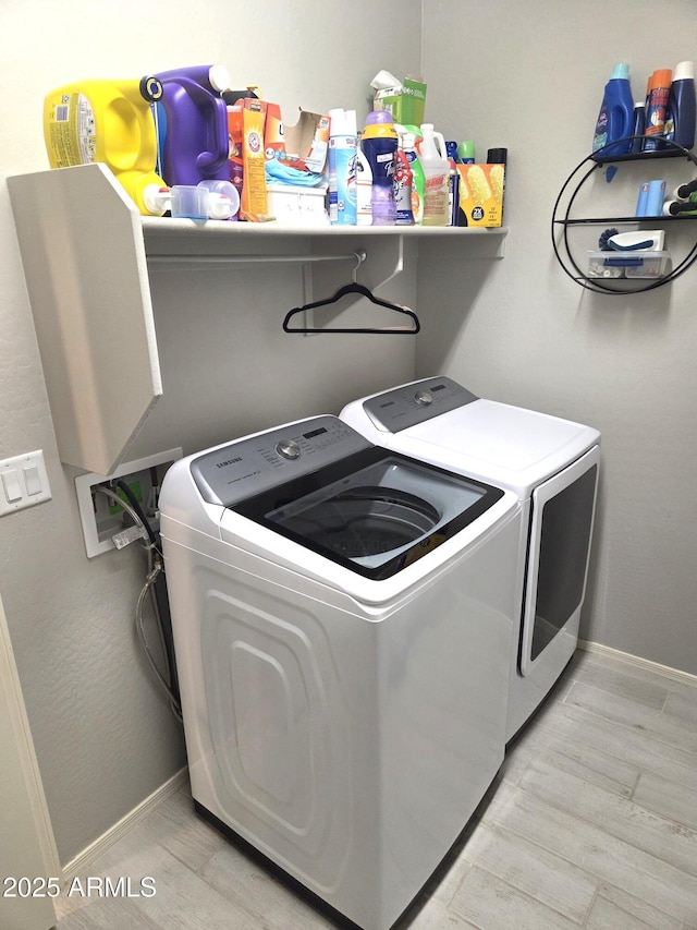 laundry room with laundry area, baseboards, separate washer and dryer, and light wood finished floors