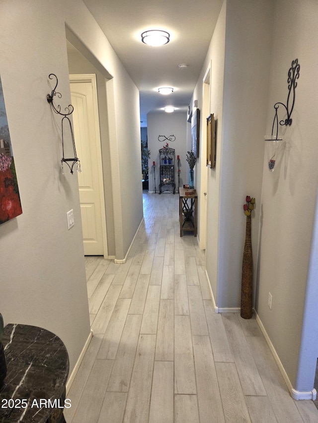 hall featuring light wood-type flooring and baseboards