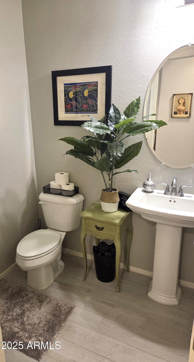 bathroom with wood finished floors, a sink, toilet, and baseboards