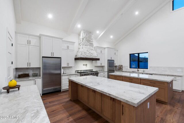kitchen with custom exhaust hood, built in fridge, backsplash, and a large island