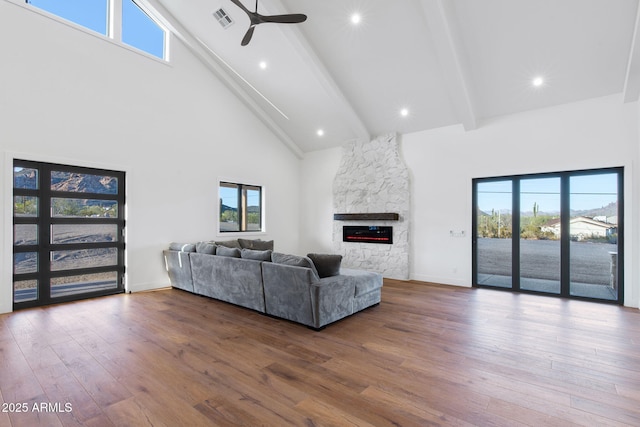 living area with visible vents, wood-type flooring, beam ceiling, a ceiling fan, and high vaulted ceiling