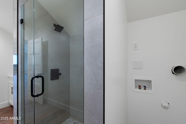 full bathroom with lofted ceiling, wood finished floors, and a stall shower