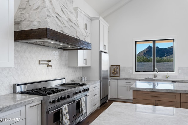 kitchen featuring stainless steel appliances, backsplash, lofted ceiling, and a sink