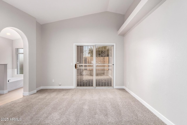 carpeted spare room featuring lofted ceiling