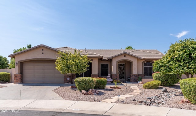 mediterranean / spanish home featuring driveway, stucco siding, a tile roof, an attached garage, and brick siding