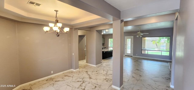 unfurnished dining area with marble finish floor, visible vents, a raised ceiling, and baseboards