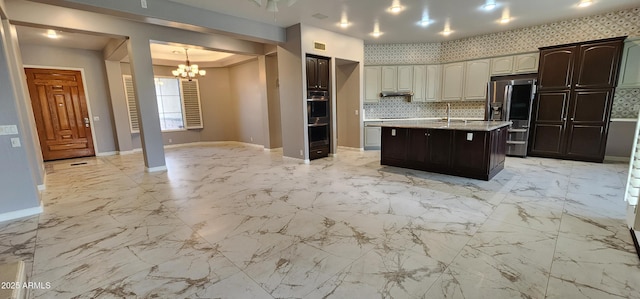 kitchen featuring stainless steel refrigerator with ice dispenser, open floor plan, a kitchen island with sink, a sink, and baseboards